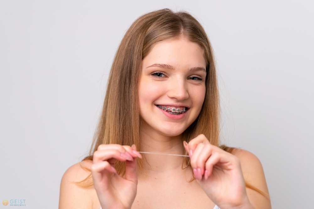 teenager russian girl with metal braces and floss isolated white background - How to Floss with Braces in Indianapolis, IN. 