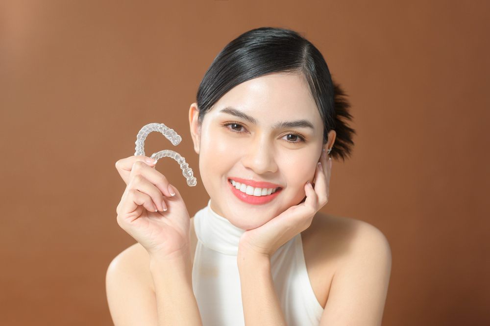 young beautiful woman holding invisalign clear aligners - Can Invisalign Fix Overbite in Indianapolis, IN.