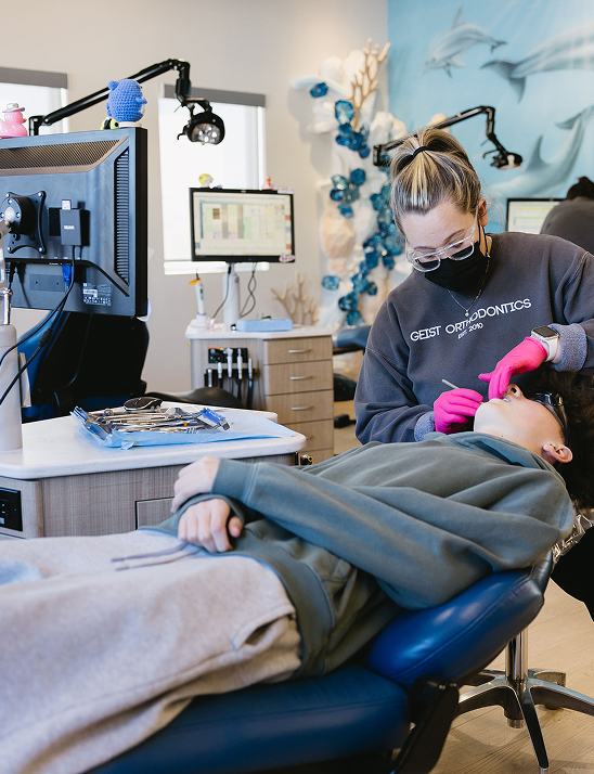 Orthodontist providing treatment to a patient in a modern clinic, featuring advanced dental equipment and a welcoming environment, reflecting Geist Orthodontics' focus on personalized care for all ages.