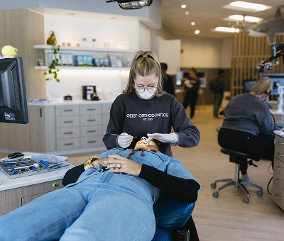 Orthodontic technician providing treatment to a patient in a modern dental office, featuring Geist Orthodontics branding, emphasizing personalized care and advanced orthodontic services.